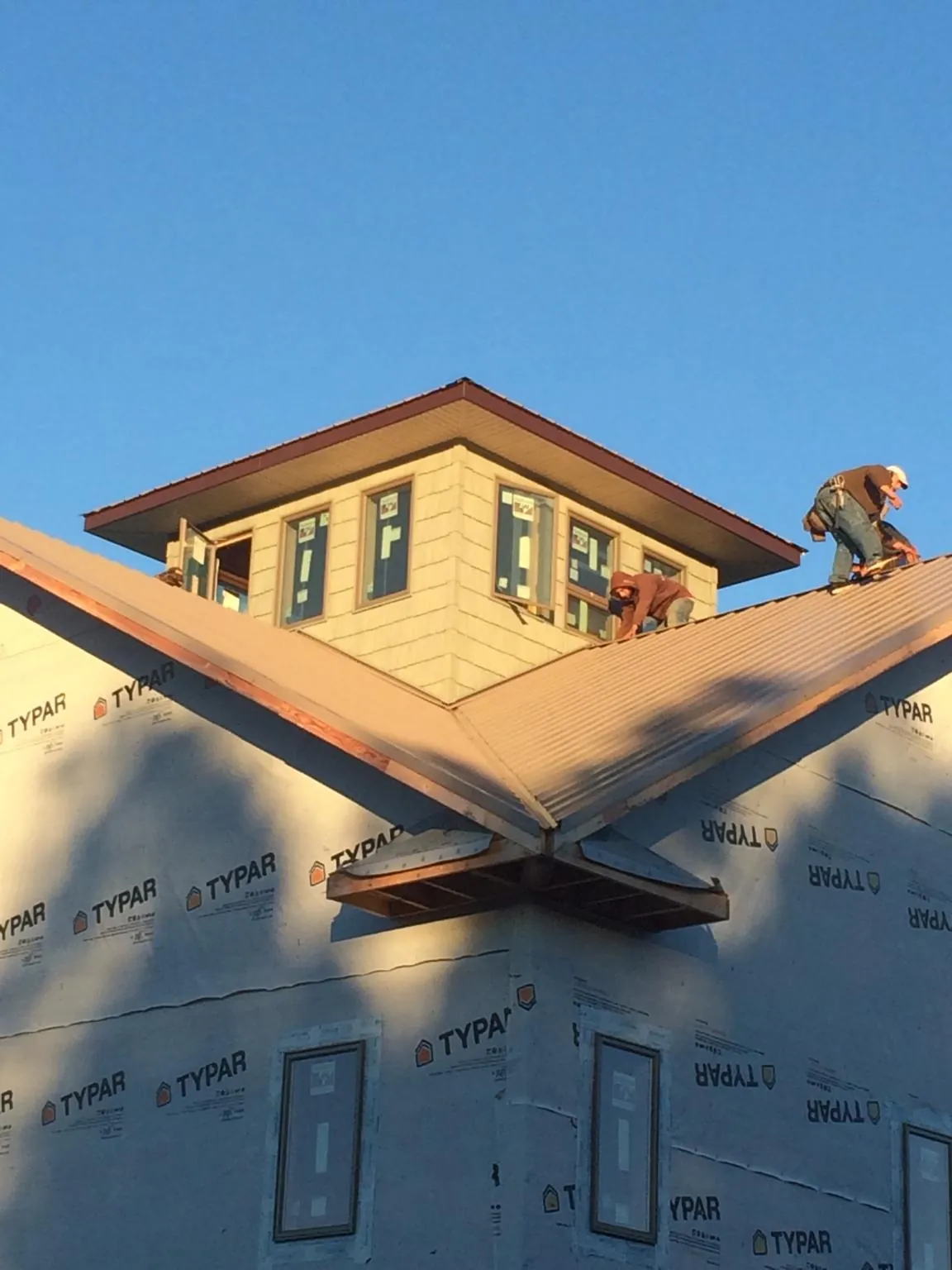Roofers working around a rooftop cupola on a new metal roof at sunset — Roof Waterproofing in Greenwich by Roofing Brothers